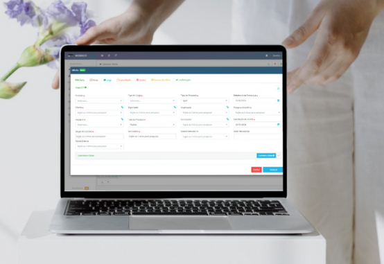 Mãos de uma pessoa sobre laptop exibindo formulário do sistema Monaco
